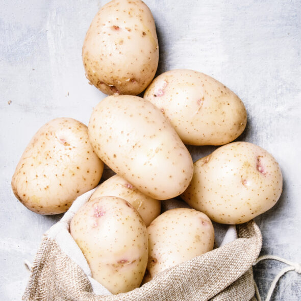 Fresh potatoes in a canvas bag, food background, top view
